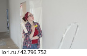 A woman with a roller hands carefully examines a wall getting ready to paint. Стоковое видео, видеограф Ольга Коваленко / Фотобанк Лори