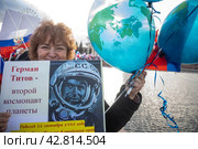 Участница космического шествия держит плакат с портретом советского космонавта Германа Титова в День космонавтики 12 апреля на ВДНХ в городе Москве, Россия (2024 год). Редакционное фото, фотограф Николай Винокуров / Фотобанк Лори