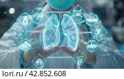 A doctor in a medical uniform demonstrating a three-dimensional holographic model of human lungs. Various icons and symbols related to medical topics are visible around the lung model. The doctor is in a clinical environment, probably an operating room or intensive care unit, with medical equipment around. This image suggests the use of advanced technologies in medicine, such as augmented reality for training, diagnosis or surgical planning. Стоковое AI-изображение, AI-художник Анна Кривицкая / Фотобанк Лори