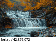 Picturesque waterfall in the forest in autumn. The water rushes forcefully over multi-level rocky rapids, creating a striking contrast with the warm colors of the autumn foliage surrounding the pond. The leaves of the trees, painted in golden and copper tones, glow against the background of dark blue water and stones, which adds peace and harmony to the scene. Стоковое AI-изображение, AI-художник Анна Кривицкая / Фотобанк Лори