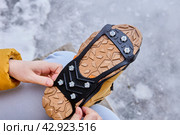 Pedestrian putting cleats on his shoes for extra traction during a winter walk during icy conditions. Стоковое фото, фотограф Владимир Григорьев / Фотобанк Лори