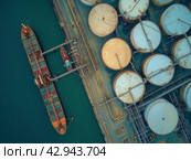 Aerial View of Cargo Ship and Storage Tanks at Industrial Port. Стоковое AI-изображение, AI-художник Кирилл Черезов / Фотобанк Лори