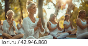 A group of retired women do yoga at sunset in the park. Banner. Стоковое AI-изображение, AI-художник Ярославский Максим / Фотобанк Лори