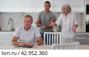 Adult man sits at table and thinks how to resolve conflict with his wife and son. Стоковое видео, видеограф Яков Филимонов / Фотобанк Лори