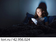 The girl lies at home in the evening on the bed with a phone in the dark. defocus. Стоковое фото, фотограф Александр Довянский / Фотобанк Лори