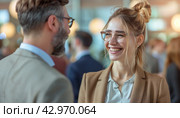 A man and woman in formal wear sharing a smile and gestures at a crowded event. Стоковое AI-изображение, AI-художник Юрий Поздников / Фотобанк Лори