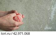 Fresh peeled grapefruit is crushed against the background of a concrete wall. Fruit in male hands. 4K. Стоковое видео, видеограф Дмитрий Кобзев / Фотобанк Лори