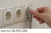 A woman hand plugs an electric cable into an outlet. Стоковое видео, видеограф Андрей Журавлев / Фотобанк Лори