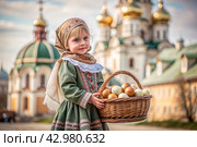 Happy bright Easter. Christianity. Portrait of a three-year-old girl in a Russian folk dress and shawl with a wicker basket with Easter eggs in her hands against the background of an Orthodox church. Стоковое AI-изображение, AI-художник Photojuli / Фотобанк Лори