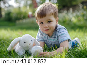 Маленький мальчик  играет с плюшевыми зайками в парке. Стоковое AI-изображение, AI-художник Щеголева Ольга / Фотобанк Лори