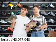 Guy with girlfriend, view specialized shoes in store, near showcase with summer trecking cross-shoes. Стоковое фото, фотограф Яков Филимонов / Фотобанк Лори