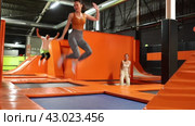 Enthusiastic middle-aged woman experiencing thrill of leaping high at vibrant trampoline gym with friends. Стоковое видео, видеограф Яков Филимонов / Фотобанк Лори