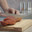 Man cuts thin slices of sausage on a wooden board with a knife. Close-up of the hands. Стоковое видео, видеограф EStarodubov / Фотобанк Лори
