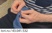 Unknown adult man sitting on the couch repairing and cuts clothes with a special blade. Стоковое видео, видеограф worker / Фотобанк Лори