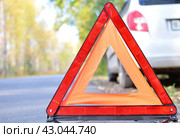 Warning stop sign on the road against the background of a white car and forest. concept of roadside assistance, travel incidents, car repair. Стоковое фото, фотограф Дмитрий Львович Алферов / Фотобанк Лори