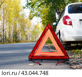 Warning stop sign on the road against the background of a white car and forest. concept of roadside assistance, travel incidents, car repair. Стоковое фото, фотограф Дмитрий Львович Алферов / Фотобанк Лори