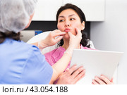Cosmetologist planning upcoming lip reshaping procedures for female patient. Стоковое фото, фотограф Яков Филимонов / Фотобанк Лори