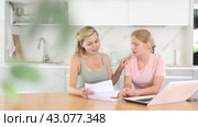 Upset teenage girl reading letter about exam results while sitting at home table with concerned mother offering comfort and understanding to daughter. Стоковое видео, видеограф Яков Филимонов / Фотобанк Лори