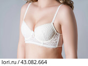 Blonde woman in white push up bra on gray background, decollete area care. Стоковое фото, фотограф Станислав Тарко / Фотобанк Лори