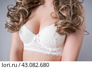 Blonde woman in white push up bra on gray background, decollete area care. Стоковое фото, фотограф Станислав Тарко / Фотобанк Лори