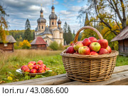 The concept of the Russian Orthodox holiday yablochny spas. A beautiful wicker basket made of vines with red ripe apples on the background of an Orthodox church. Стоковое AI-изображение, AI-художник Photojuli / Фотобанк Лори