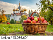The concept of the Russian Orthodox holiday yablochny spas. A beautiful wicker basket made of vines with red ripe apples on the background of an Orthodox church. Стоковое AI-изображение, AI-художник Photojuli / Фотобанк Лори