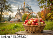 The concept of the Russian Orthodox holiday yablochny spas. A beautiful wicker basket made of vines with red ripe apples on the background of an Orthodox church. Стоковое AI-изображение, AI-художник Photojuli / Фотобанк Лори