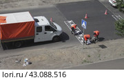 ANGARSK, IRKUTSK REGION, RUSSIA - July 29, 2023: Video of team of road workers in orange safety vests applying markings to speed bump with white paint. Summer road works. View from above. Редакционное видео, видеограф Виктория Катьянова / Фотобанк Лори