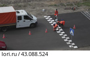 ANGARSK, IRKUTSK REGION, RUSSIA - July 29, 2023: Sesonal road works. Video of team of workers in orange vests marking speed bump with white paint in form of signal squares on summer day. Top view. Редакционное видео, видеограф Виктория Катьянова / Фотобанк Лори