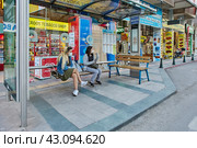Just before curfew, young Turkish women wait for public transport while sitting on bus stop bench. (2021 год). Редакционное фото, фотограф Владимир Григорьев / Фотобанк Лори