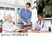 three positive doctors are sitting at table animatedly and actively discussing current work. Стоковое фото, фотограф Яков Филимонов / Фотобанк Лори