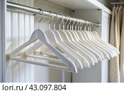 Close-up of white hangers on a white closet. The concept of order and storage in the house. Стоковое AI-изображение, AI-художник Photojuli / Фотобанк Лори