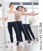 Pretty young girl in black and white sportswear, participating 2nd position of ballet stance at barre with group in choreography studio. Стоковое фото, фотограф Яков Филимонов / Фотобанк Лори