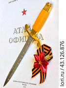 Кортик офицерский ВВС СССР (ЗИК, 1952 год) и георгиевская лента с пятиконечной звездой на фоне титульного листа атласа офицера (2024 год). Редакционное фото, фотограф Владимир Литвинов / Фотобанк Лори