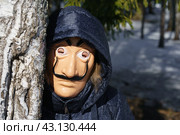 Moscow region, Russia - March 17, 2023: Somebody put on Salvador Dali mask, peeks out birch tree in the spring Russian forest. Sunny day. Blue sky. Bright sun. Abstraction. Close up. Редакционное фото, фотограф YuryKara / Фотобанк Лори