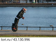 Moscow, Russia - April 14, 2023: Man driving Electric unicycle on the street . Riding on the street. He has sport activity in sunny spring day. Mobility in the big city. Real futuristic people. Редакционное фото, фотограф YuryKara / Фотобанк Лори
