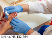 The mother holds the child's hand, and the nurse wipes the finger with a disinfecting swab, sterilizing it before taking blood. Стоковое фото, фотограф Андрей С / Фотобанк Лори