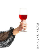 The hand of a girl in an evening black dress holds a glass with red wine. parties, birthday and christmas celebrations. Стоковое фото, фотограф Дмитрий Львович Алферов / Фотобанк Лори