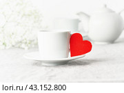 Valentine's Day. Morning breakfast for two with tea and flowers. Red felt heart is symbol of lovers. Стоковое фото, фотограф Natalia Gdovskaia / Фотобанк Лори