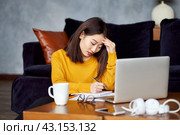 Asian woman working at home, writing notebook, freelancer. Overworking, filling out papers. Стоковое фото, фотограф Natalia Gdovskaia / Фотобанк Лори