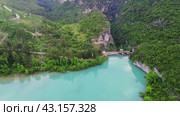 Drone view of mountain turquoise lake and dam. Dam spans lake, highlighting water management. Turquoise lake reflects surrounding landscape. Dam interaction with lake is evident (2024 год). Редакционное видео, видеограф ILIA GOROKHOV / Фотобанк Лори