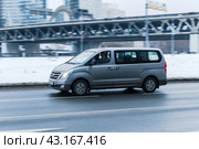 Hyundai H-1 in the city street in motion. Side view of gray color large Hyundai Grand Starex MPV minivan on winter road. Редакционное фото, фотограф Константин Григорьев / Фотобанк Лори