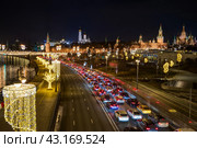Москва, Россия. Вид сверху на Москворецкую набережную. На проезжей части автомобильная пробка. Множество автомобилей в дорожном заторе. Вдали Московский Кремль. Красивое уличное освещение и новогодние гирлянды на фонарях. Стоковое фото, фотограф Андрей Степанов / Фотобанк Лори