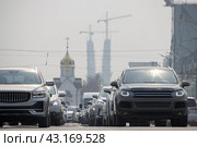 Автомобили на проезжей части. Вдали православная часовня и строительство опор автомобильного вантового моста. Дорожное движение в большом городе. Красный проспект, город Новосибирск, Новосибирская область, Сибирь, Россия. (2023 год). Стоковое фото, фотограф Андрей Степанов / Фотобанк Лори