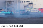 The blue drift car spins circles around the second black car at the Mega Belaya Dacha site. Russia. Moscow. 19.05.2024. Редакционное видео, видеограф Ярославский Максим / Фотобанк Лори