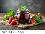 A jar of homemade strawberry, healthy jam with mint on a black background. Conservation and harvesting in summer. Стоковое AI-изображение, AI-художник Photojuli / Фотобанк Лори