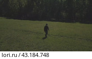 A young man walks through a spring meadow on a sunny day. Spring nature. A distant panorama. Стоковое видео, видеограф Ярославский Максим / Фотобанк Лори