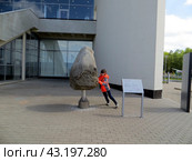 Государственный музей истории космонавтики имени К. Э. Циолковского в Калуге.Открытая образовательно-игровая выставка "Пять тонн скалы". Девочка пытается повернуть скалу. Россия. (2024 год). Редакционное фото, фотограф Мария Фетисова / Фотобанк Лори