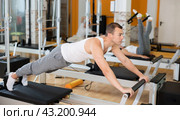 Man in different poses performs static and dynamic exercises on reformer. Стоковое фото, фотограф Яков Филимонов / Фотобанк Лори