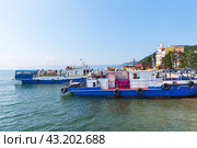 LISTVYANKA VILLAGE, IRKUTSK REGION, RUSSIA - August 03, 2023: View of Baikal Lake embankment in village of Listvyanka, pleasure boats and popular Mayak hotel on sunny summer day. Редакционное фото, фотограф Виктория Катьянова / Фотобанк Лори